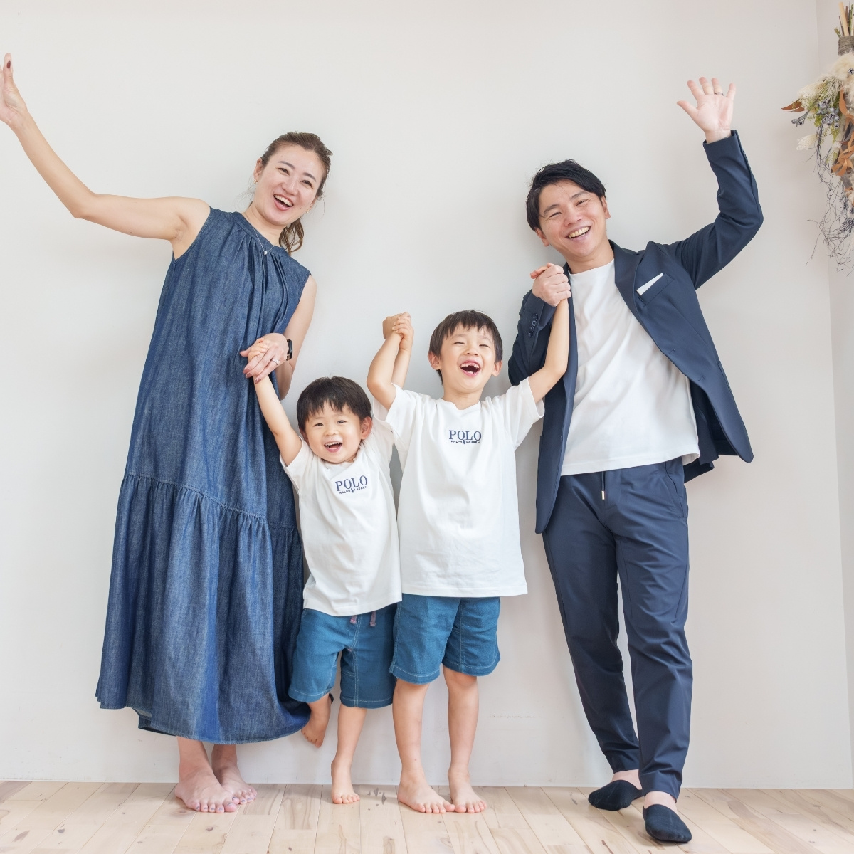 家族4人で手をつないで両手を上げる、結婚記念日の家族写真
