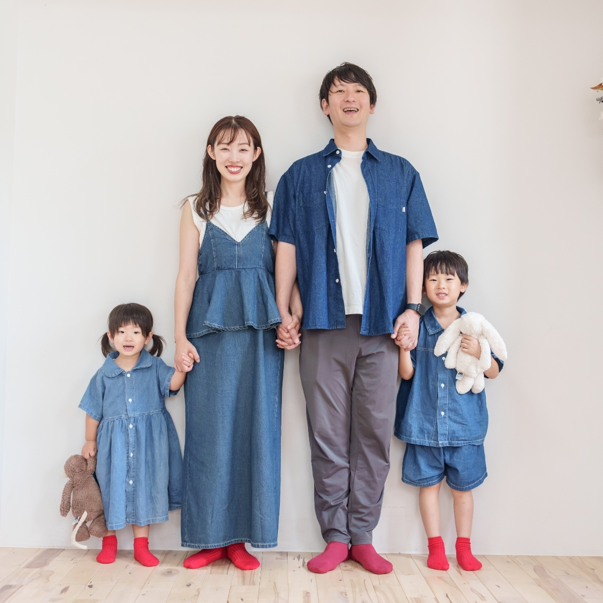 デニムのお揃いコーデと赤いソックスで揃えた家族4人の写真
