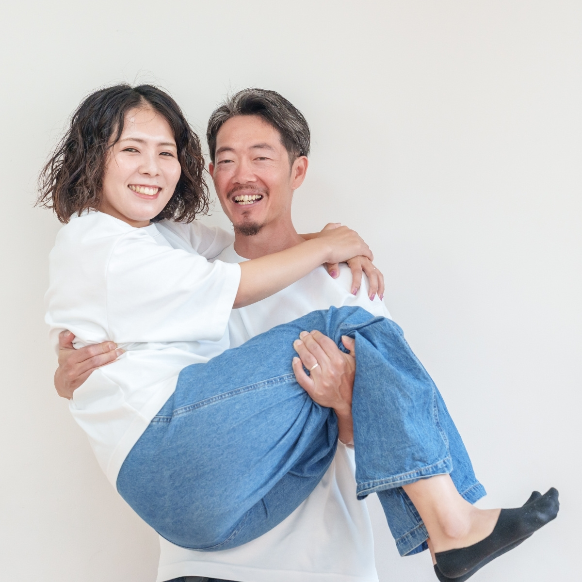 ご主人がお姫様抱っこをする、笑顔のご夫婦2人の写真