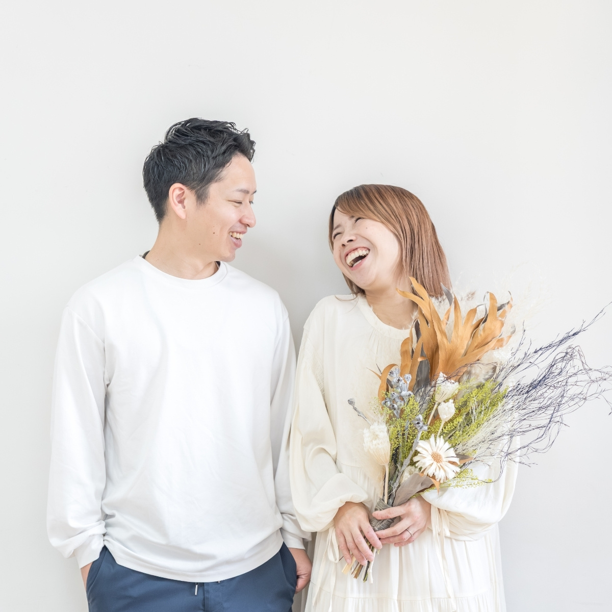 花束を持って笑い合うご夫婦2人の写真